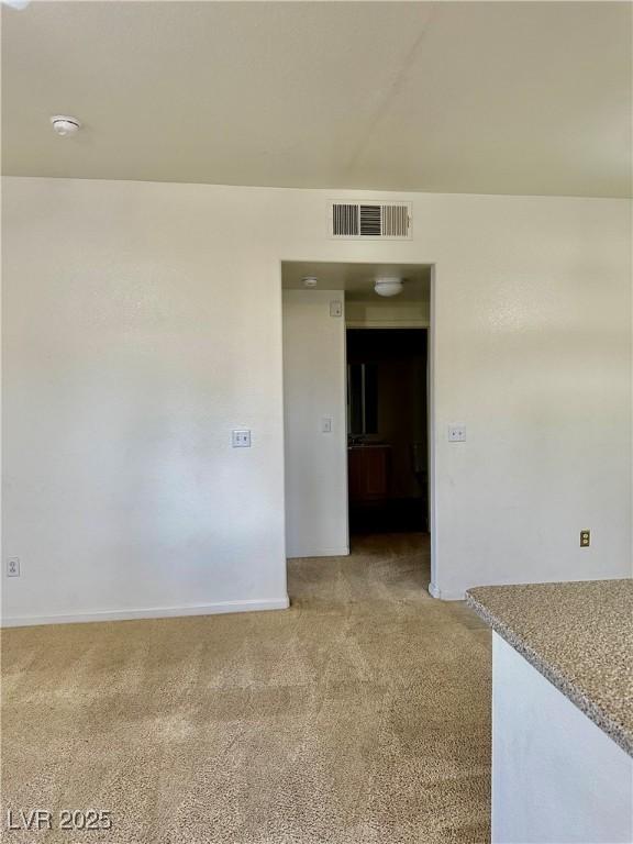 spare room with light colored carpet, visible vents, and baseboards