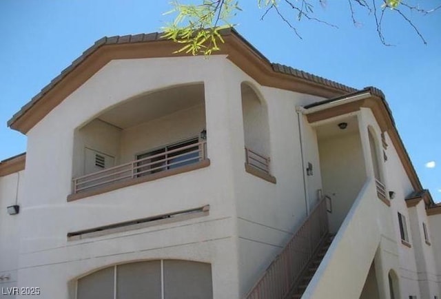 view of home's exterior with a tile roof, a balcony, and stucco siding