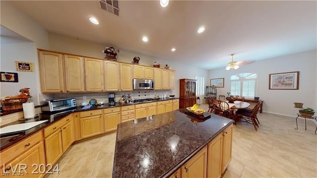 kitchen featuring stainless steel microwave, decorative backsplash, visible vents, and light brown cabinetry