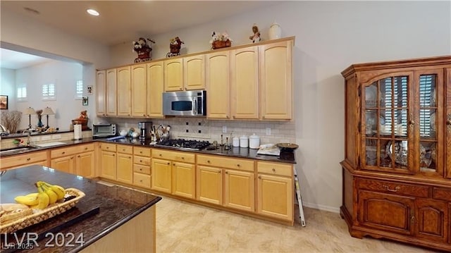 kitchen with a healthy amount of sunlight, light brown cabinets, a sink, stainless steel appliances, and backsplash