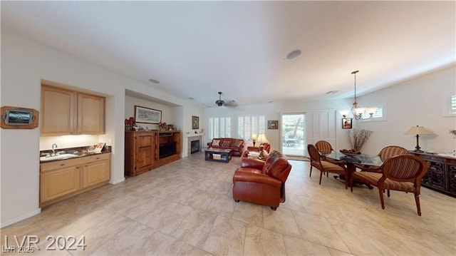 living room featuring ceiling fan with notable chandelier and a fireplace