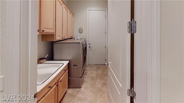 washroom with a sink, cabinet space, and separate washer and dryer