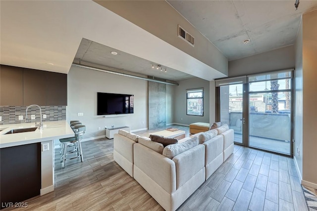 living room with baseboards, visible vents, and light wood finished floors