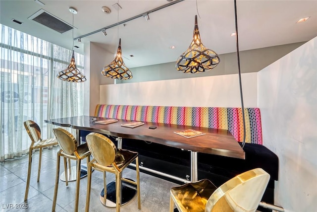 dining room with tile patterned floors, rail lighting, and expansive windows