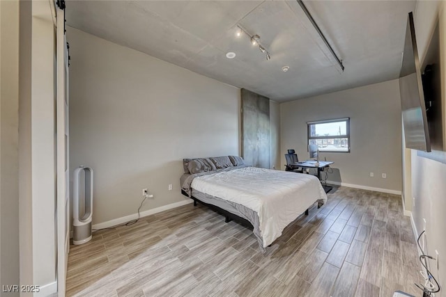 bedroom featuring baseboards, track lighting, and light wood finished floors