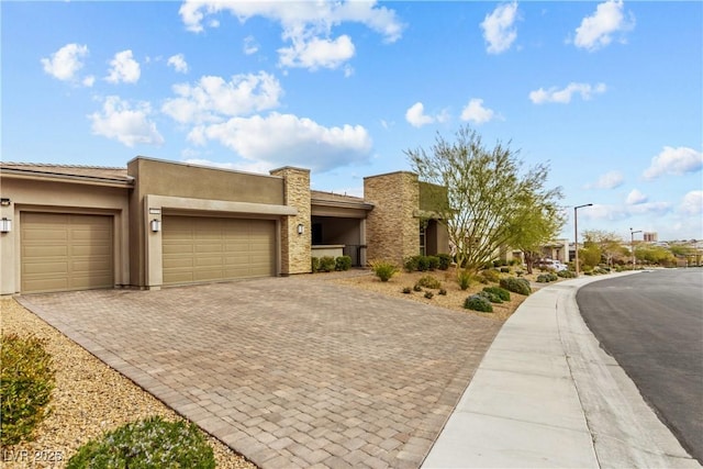 view of front of property with decorative driveway, an attached garage, and stucco siding