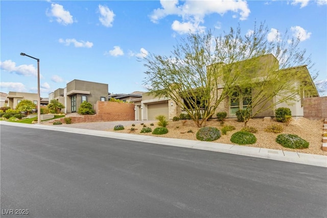 southwest-style home featuring a residential view, an attached garage, driveway, and fence