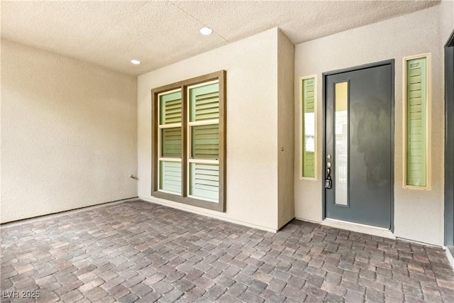 view of exterior entry featuring a patio area and stucco siding