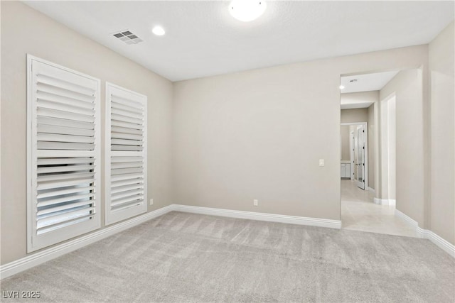 empty room featuring light carpet, visible vents, and baseboards