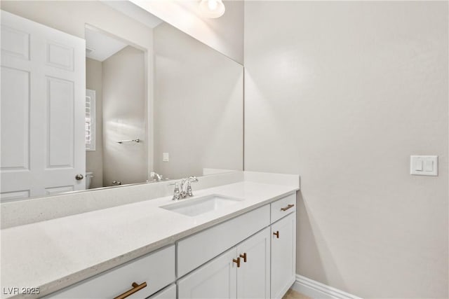 bathroom with vanity, toilet, and baseboards