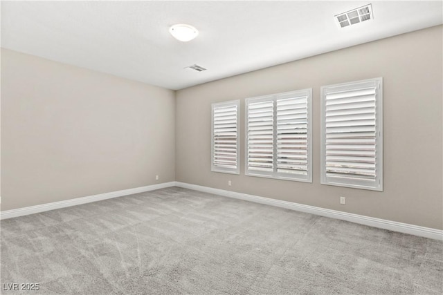 empty room with carpet, visible vents, and baseboards