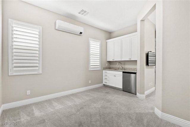 interior space with visible vents, a sink, stainless steel dishwasher, white cabinetry, and a wall unit AC