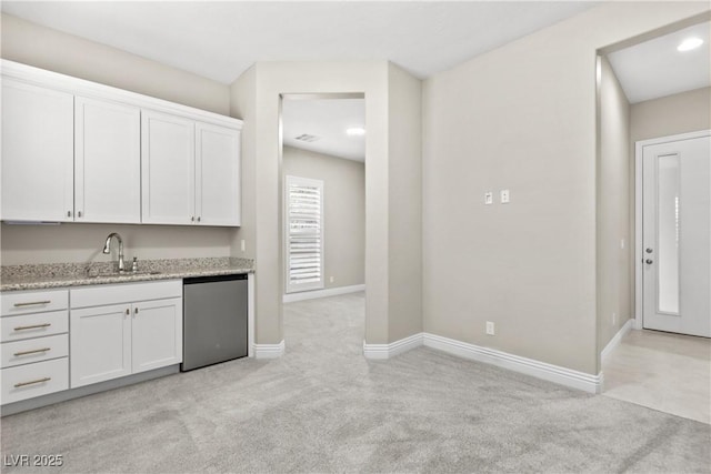 kitchen with light carpet, a sink, white cabinetry, baseboards, and dishwasher