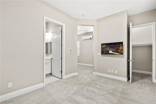 unfurnished bedroom with a spacious closet, baseboards, light colored carpet, an AC wall unit, and a closet