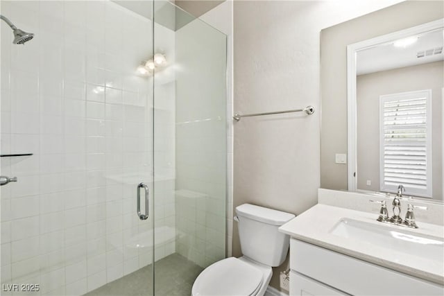 bathroom with visible vents, toilet, a stall shower, and vanity