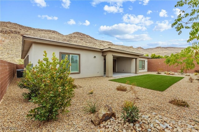 rear view of house with a patio area, stucco siding, a mountain view, and fence