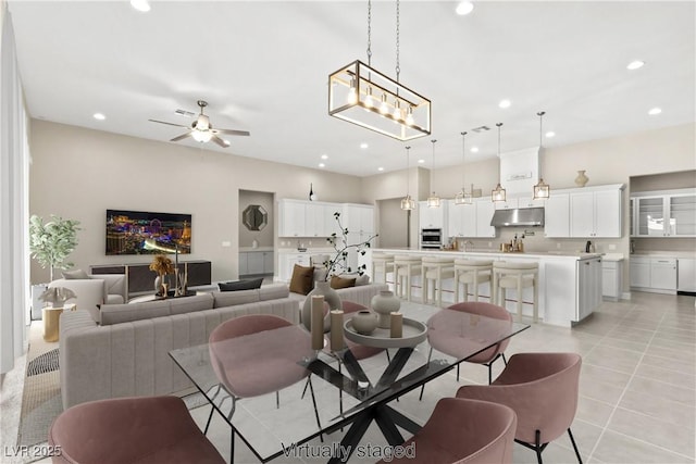 living area with light tile patterned floors, recessed lighting, and ceiling fan with notable chandelier