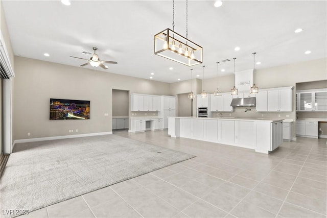 kitchen with a large island, under cabinet range hood, stainless steel oven, recessed lighting, and open floor plan