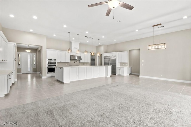 kitchen featuring under cabinet range hood, light tile patterned floors, light carpet, and stainless steel appliances