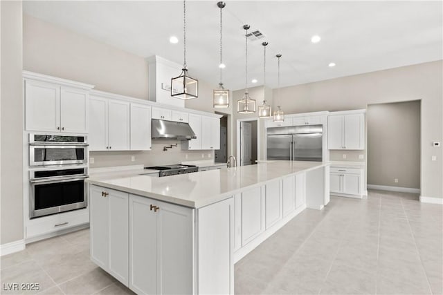 kitchen with a spacious island, under cabinet range hood, light countertops, appliances with stainless steel finishes, and white cabinets