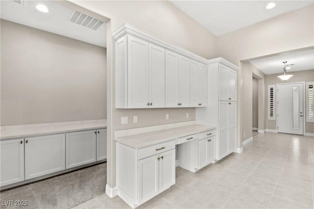 kitchen featuring visible vents, built in desk, white cabinetry, recessed lighting, and light countertops