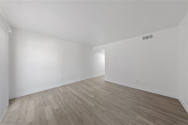 empty room featuring visible vents, baseboards, and wood finished floors