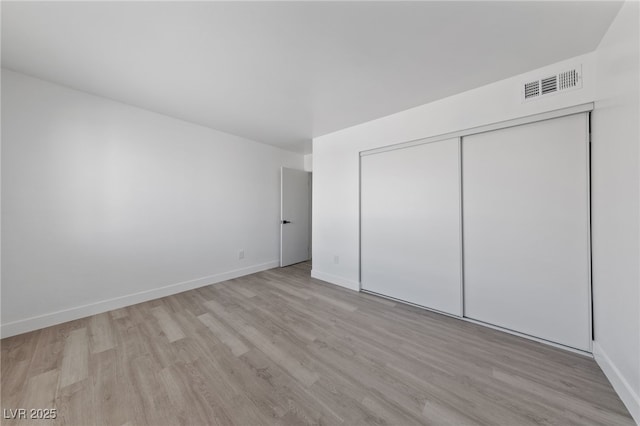 unfurnished bedroom featuring a closet, visible vents, baseboards, and wood finished floors