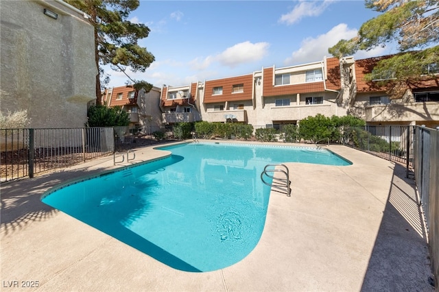 pool featuring a patio area, fence, and a residential view