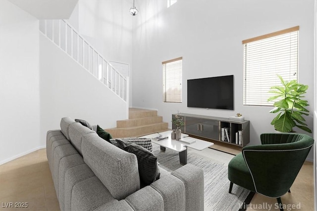 living room with stairway, baseboards, and a towering ceiling