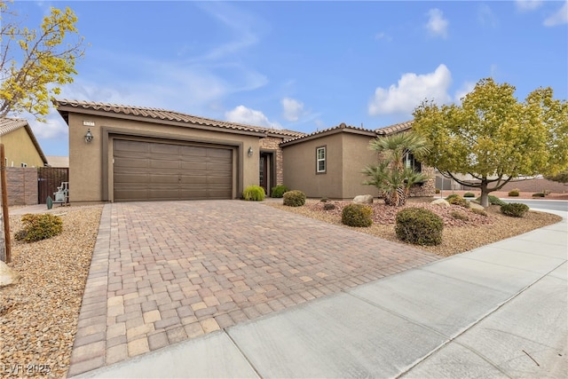 mediterranean / spanish-style home with stucco siding, decorative driveway, fence, an attached garage, and a tiled roof