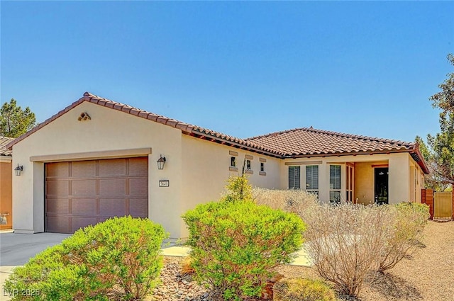 mediterranean / spanish home featuring a garage, a tile roof, driveway, and stucco siding