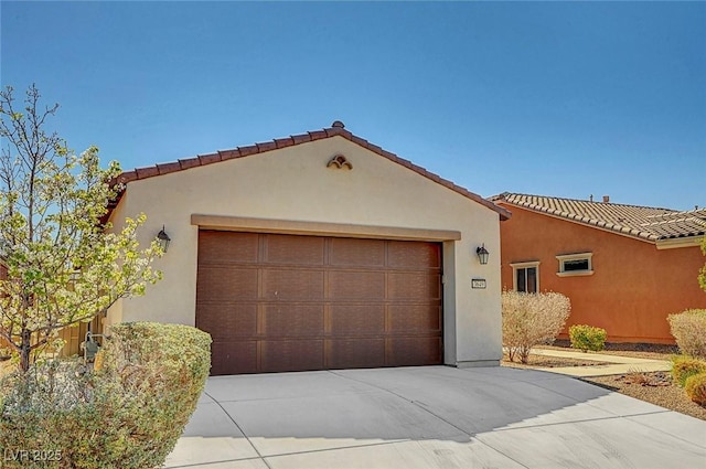 view of front of property featuring a tiled roof, a garage, driveway, and stucco siding