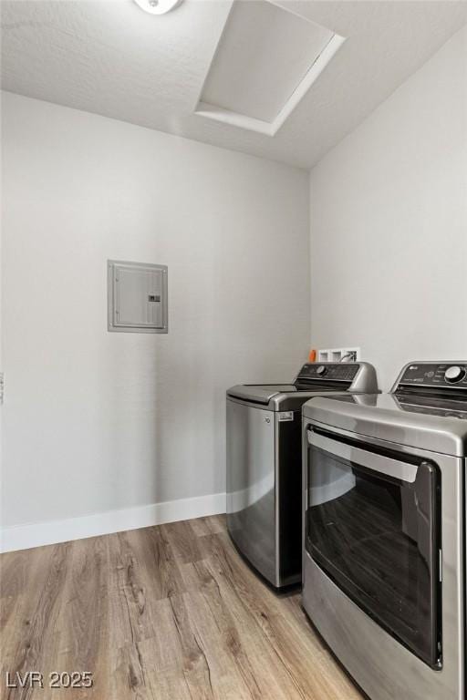 clothes washing area featuring laundry area, washing machine and dryer, attic access, and light wood-style flooring