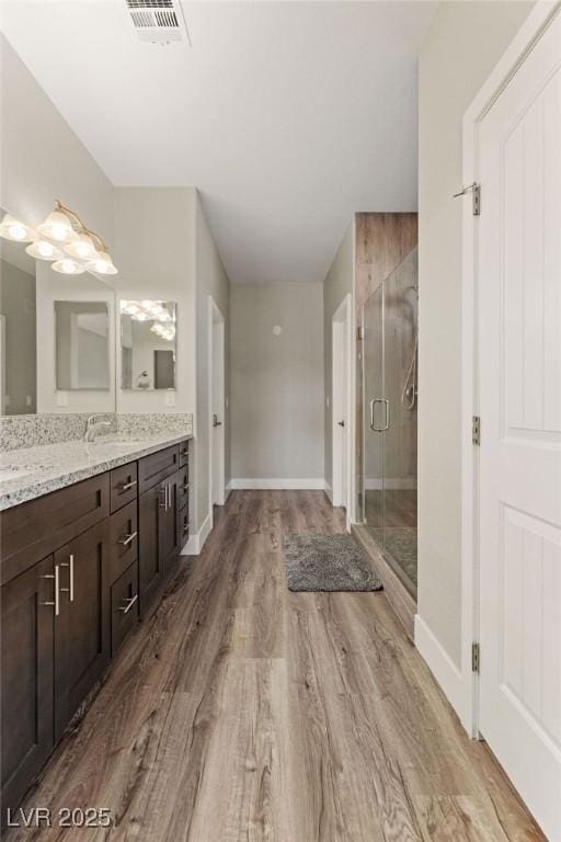 bathroom with visible vents, a stall shower, wood finished floors, baseboards, and vanity