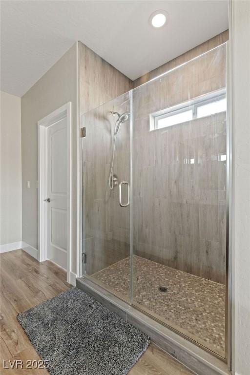 bathroom with a stall shower, baseboards, and wood finished floors