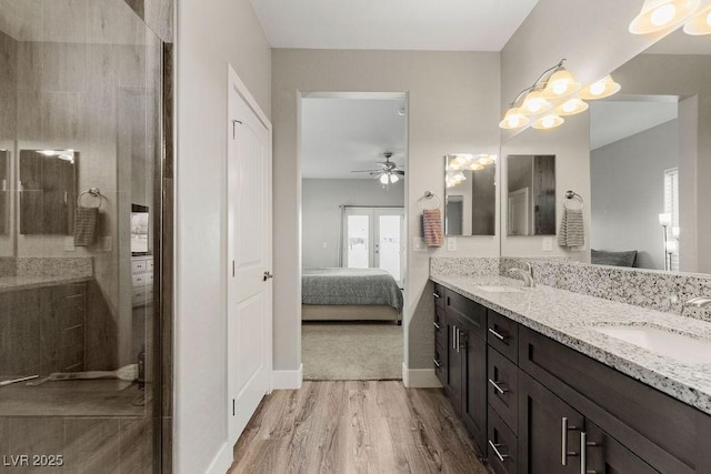 ensuite bathroom with double vanity, wood finished floors, ensuite bath, and a sink