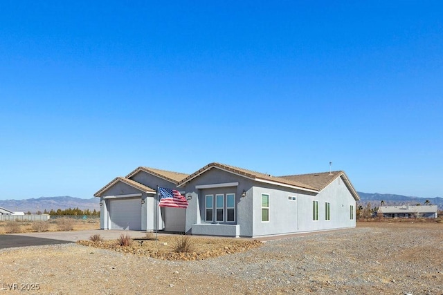 view of front of house with an attached garage, a mountain view, driveway, and stucco siding