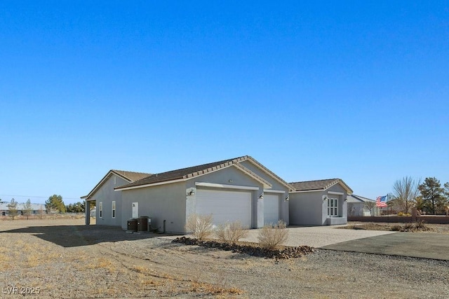 view of front of property featuring cooling unit, stucco siding, an attached garage, and driveway