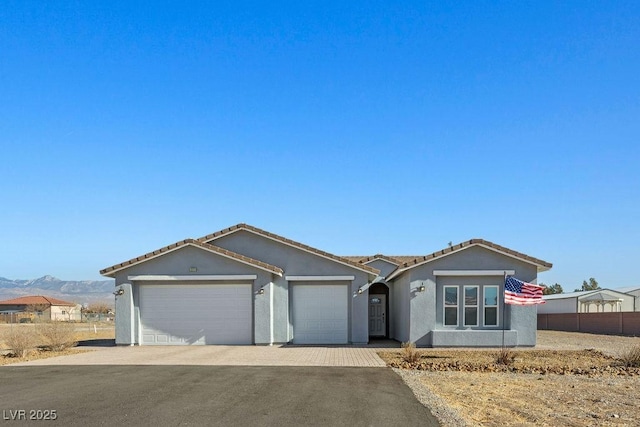 single story home with stucco siding, a tile roof, decorative driveway, fence, and a garage