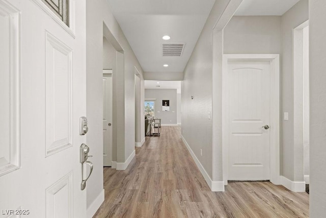 hallway featuring light wood-type flooring, visible vents, baseboards, and recessed lighting