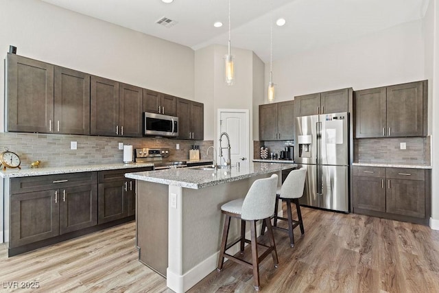 kitchen with visible vents, a sink, dark brown cabinets, appliances with stainless steel finishes, and light wood-type flooring