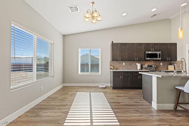 kitchen with visible vents, light wood-style flooring, dark brown cabinetry, appliances with stainless steel finishes, and lofted ceiling