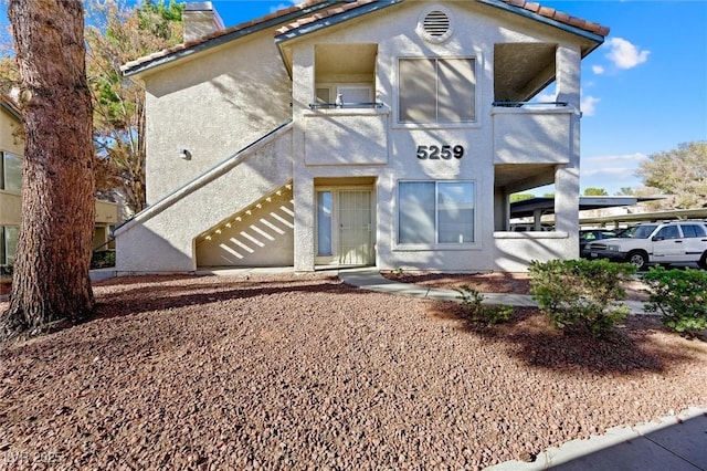 view of front of property with stucco siding, a chimney, and a tiled roof