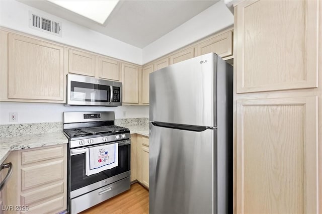 kitchen with stainless steel appliances, visible vents, light wood-style flooring, and light brown cabinets