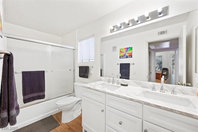 full bathroom featuring double vanity, visible vents, wood finished floors, and a sink