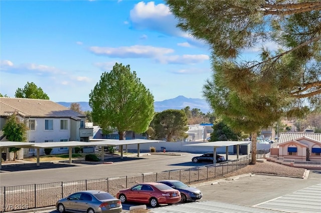 uncovered parking lot with fence, a mountain view, and a residential view