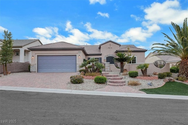 view of front of home with a tiled roof, stucco siding, decorative driveway, stone siding, and an attached garage