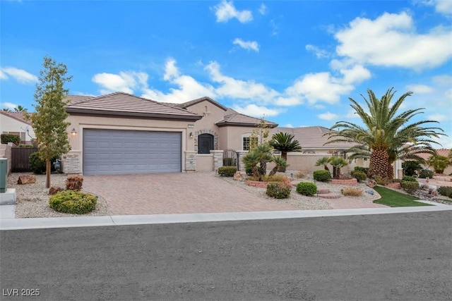 view of front of house with fence, an attached garage, stucco siding, a tiled roof, and decorative driveway