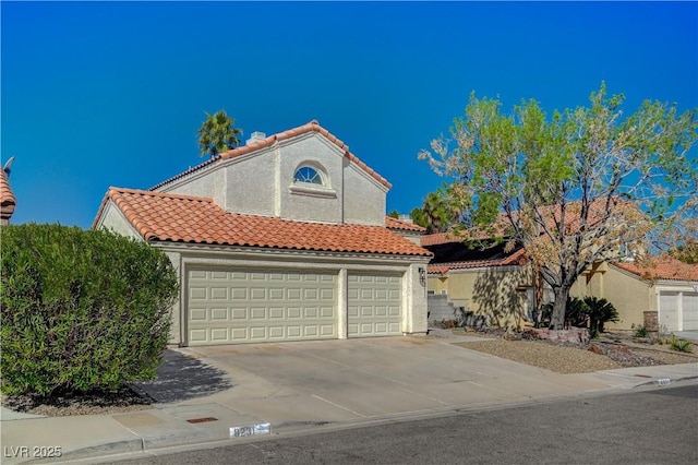 mediterranean / spanish home featuring concrete driveway, a tiled roof, a garage, and stucco siding