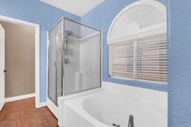 bathroom with wood finished floors, a garden tub, and a stall shower